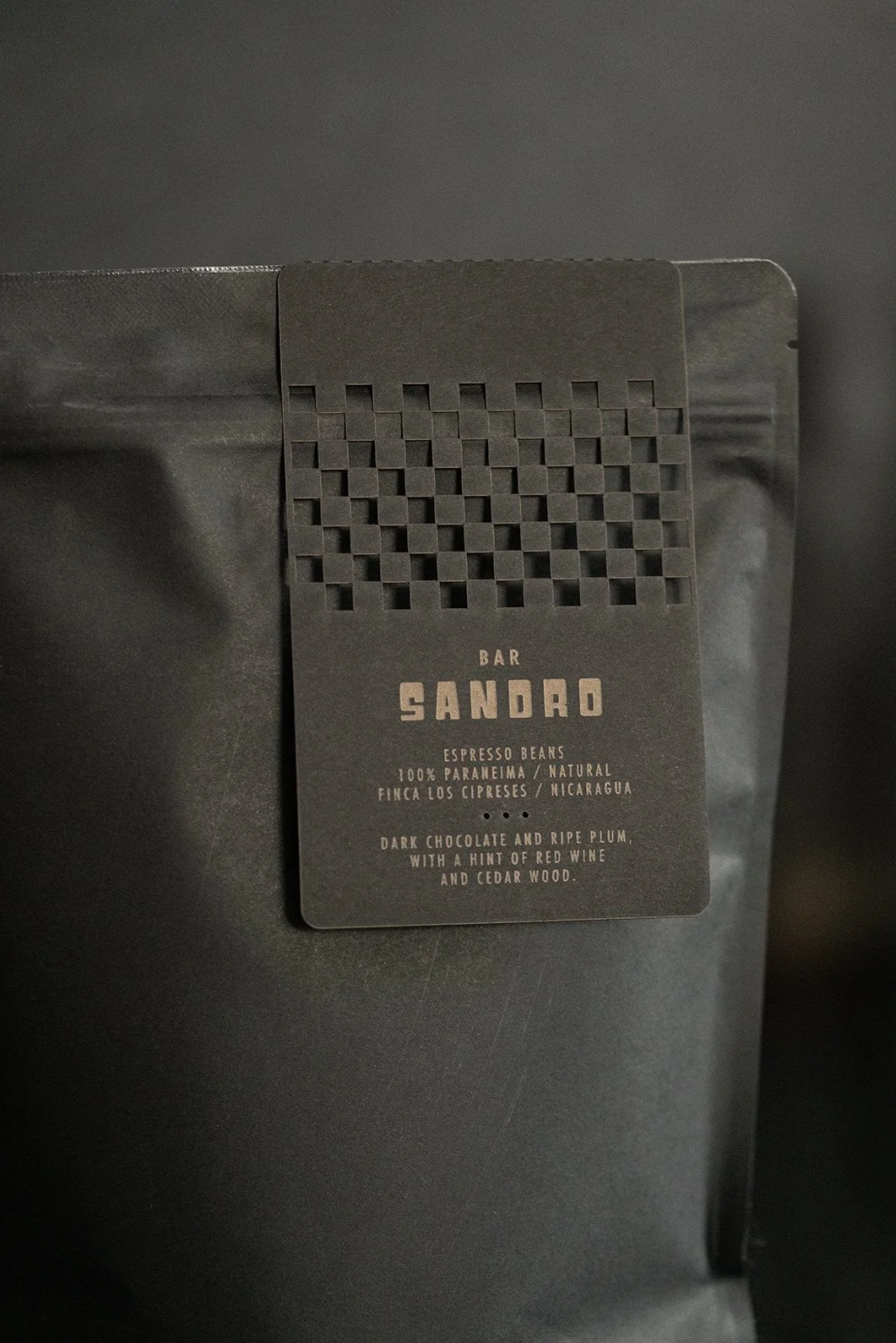 Bar Sandro espresso beans bag: a matte black pouch with a laser-cut checkerboard label reading 100% Parainema, natural, Finca Los Cipreses, Nicaragua