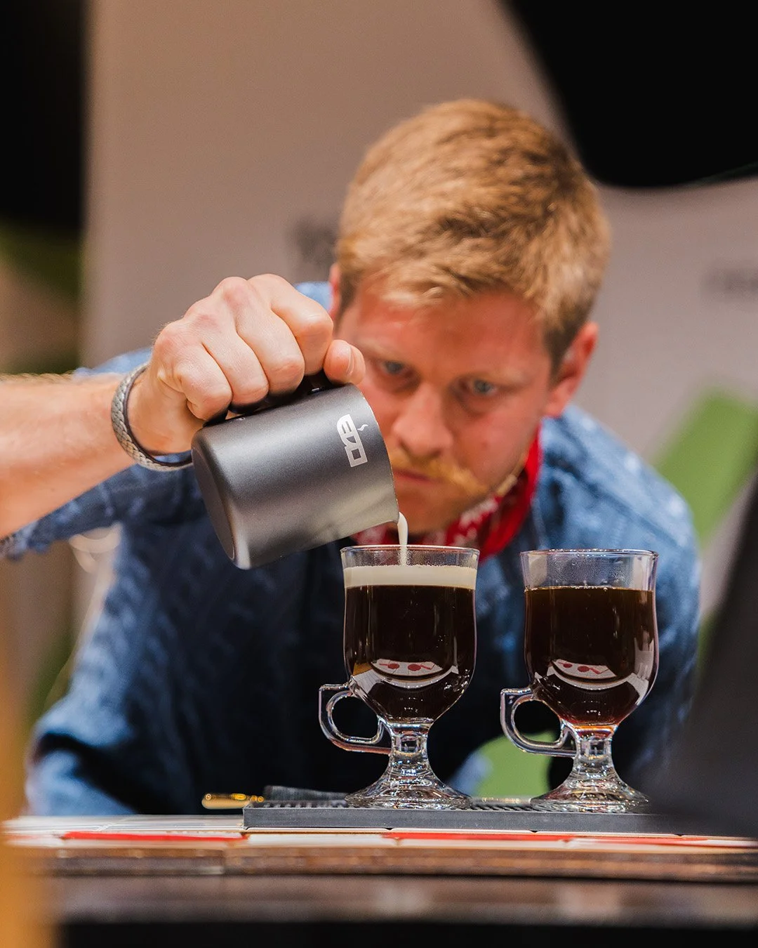 Close-up of Sandro floating cream onto two Irish-style coffee cocktails