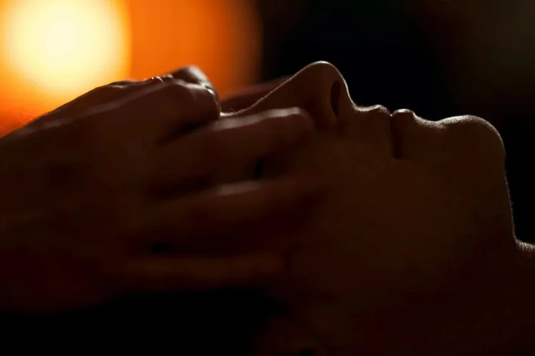 person receiving a scalp massage in a candlelit room