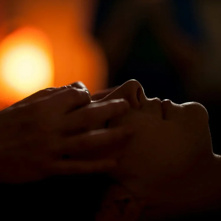 person receiving a scalp massage in a candlelit room
