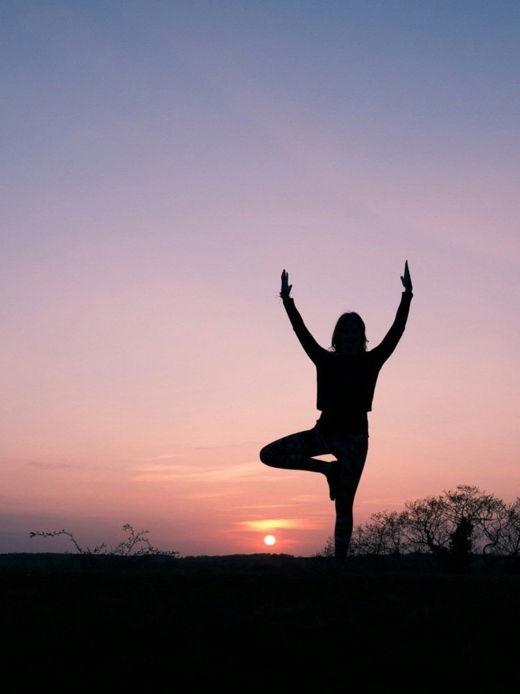 Woman outside at sunset standing in tree pose