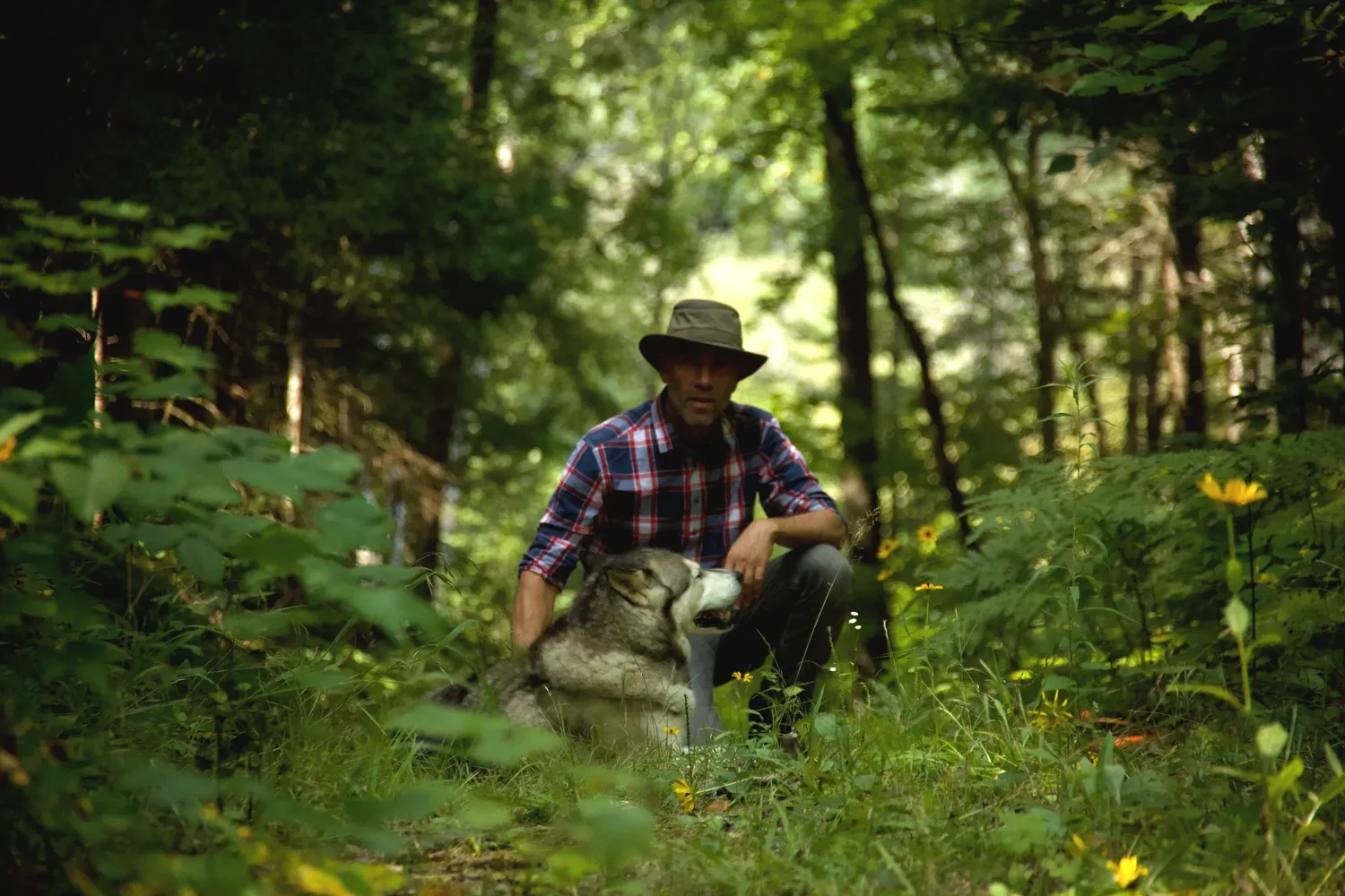 Ranger Steve crouched beside Inook, his dog, in the LeTerrain forest
