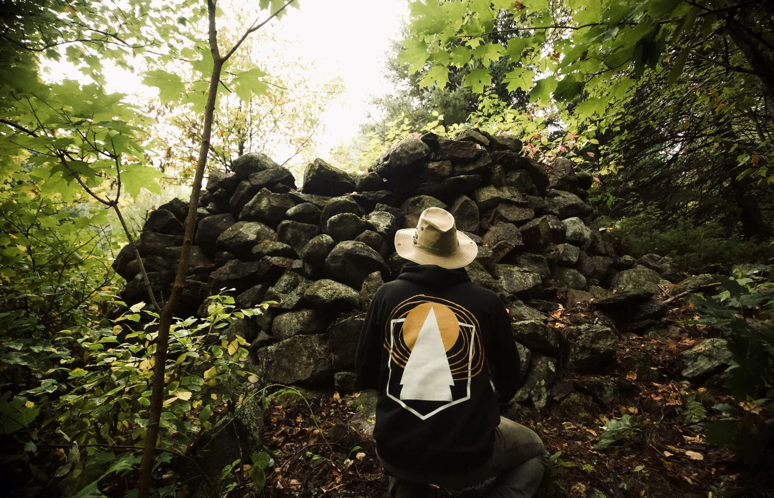 A visitor kneeling before one of the ancient stone cairns at LeTerrain