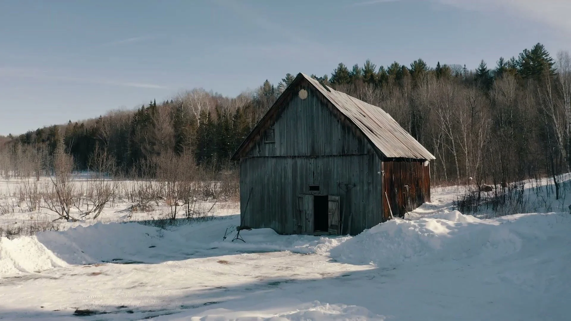 Une grange d&eacute;lav&eacute;e dans la neige &eacute;paisse &agrave; la lisi&egrave;re de la for&ecirc;t, tir&eacute;e du film