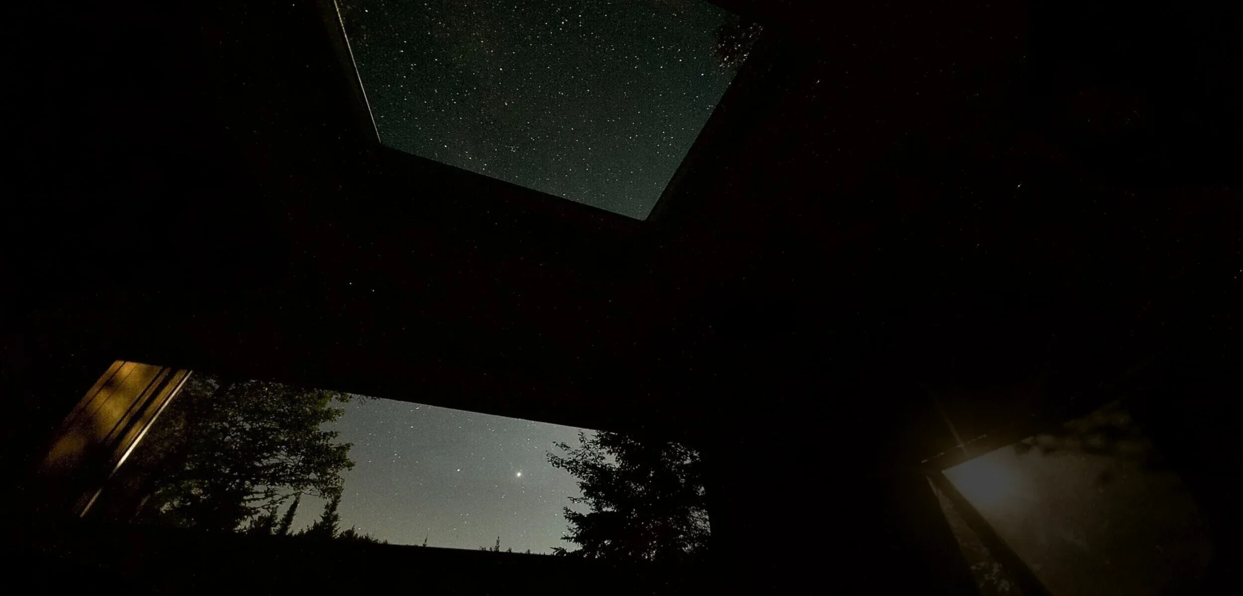 La vue vers le haut depuis l&rsquo;int&eacute;rieur de Stargate&nbsp;: le puits de lumi&egrave;re rempli d&rsquo;&eacute;toiles, la fen&ecirc;tre donnant sur la cime des arbres