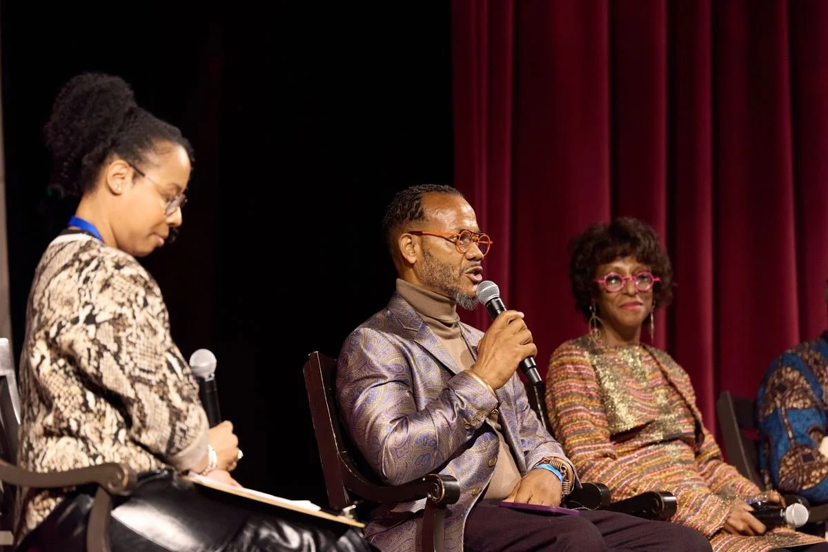 Panelists speaking into microphones on stage