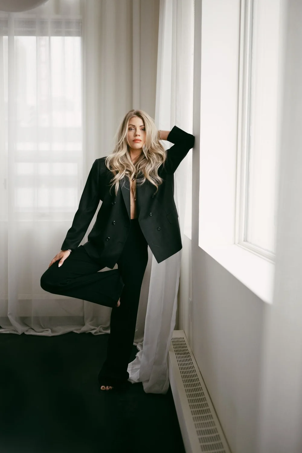 Lauren Larsen in an oversized double-breasted suit by the window