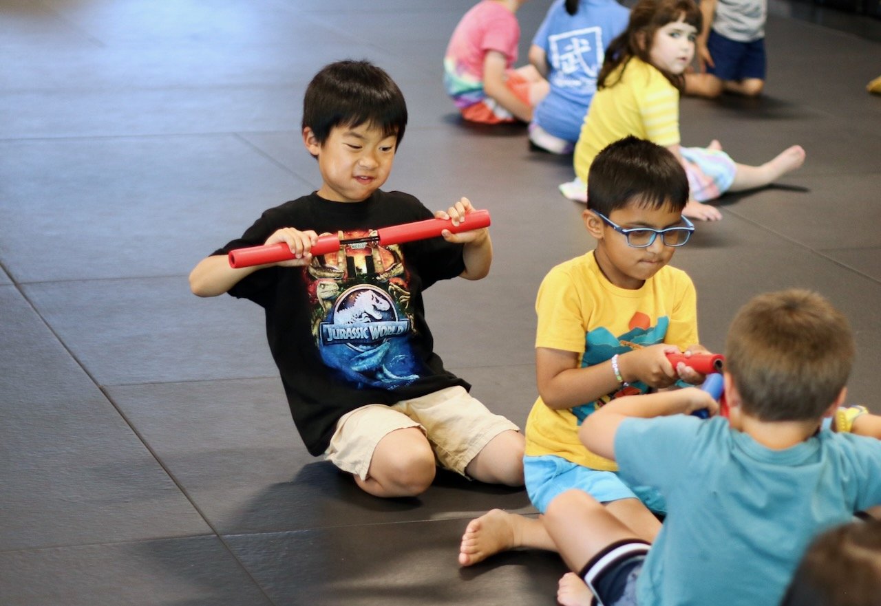 A boy squints his face in effort as he tests the strength of foam nunchucks.