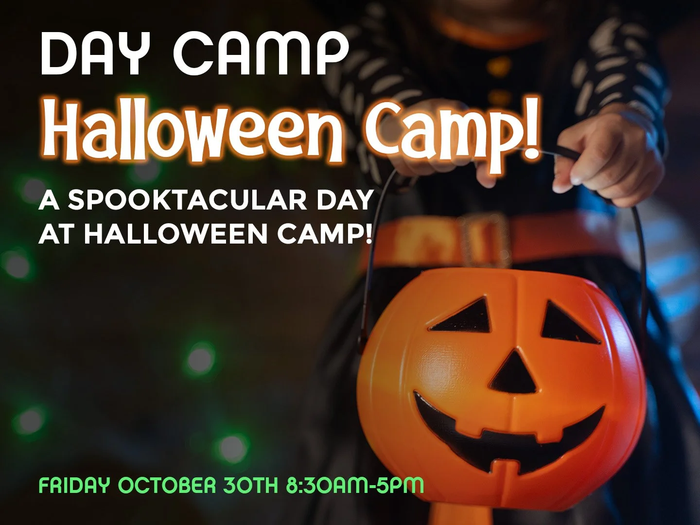 At night, a girl in costume holds out her plastic pumpkin bucket for candy.