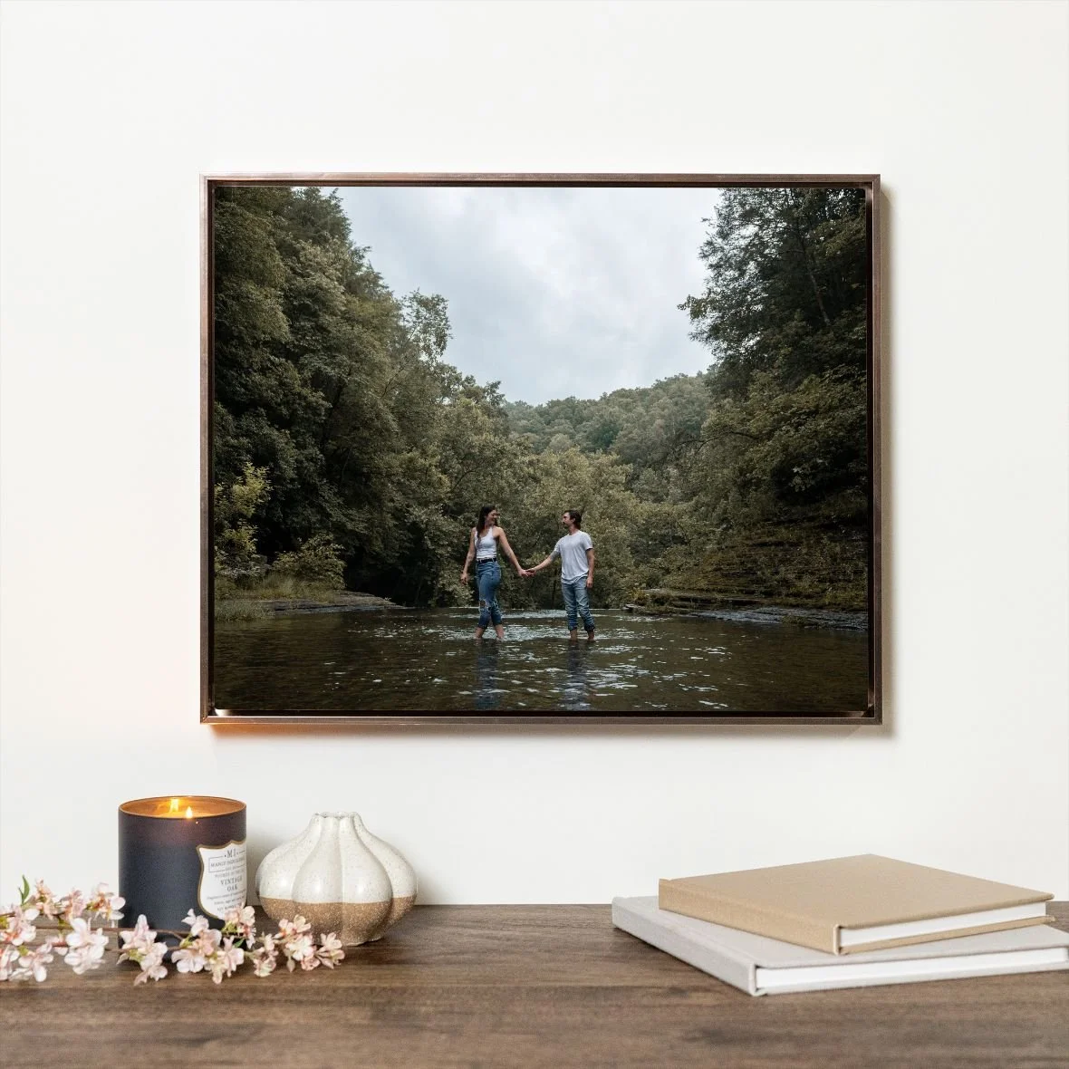 Float-framed photograph above a console styled with candles, flowers, and books
