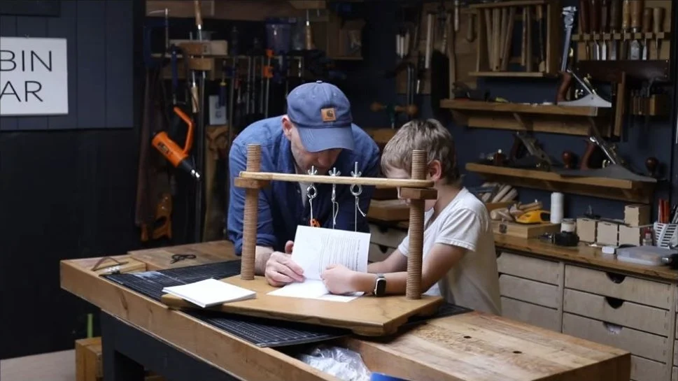 Sewing the book of tool plans on our handmade wooden sewing frame