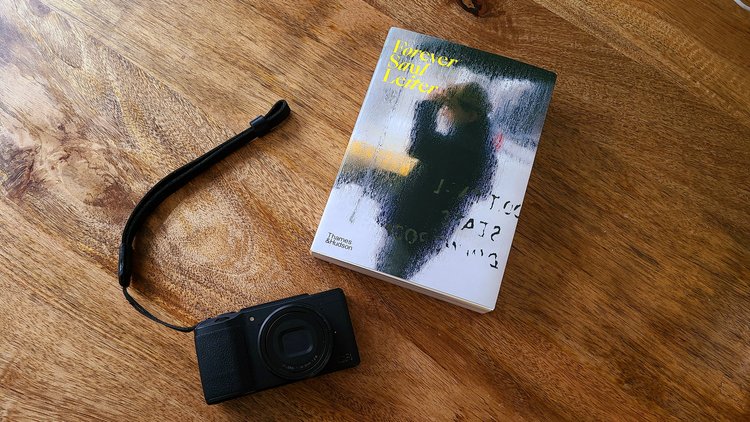 A picture of a camera and a Saul Leiter photo book on a table.