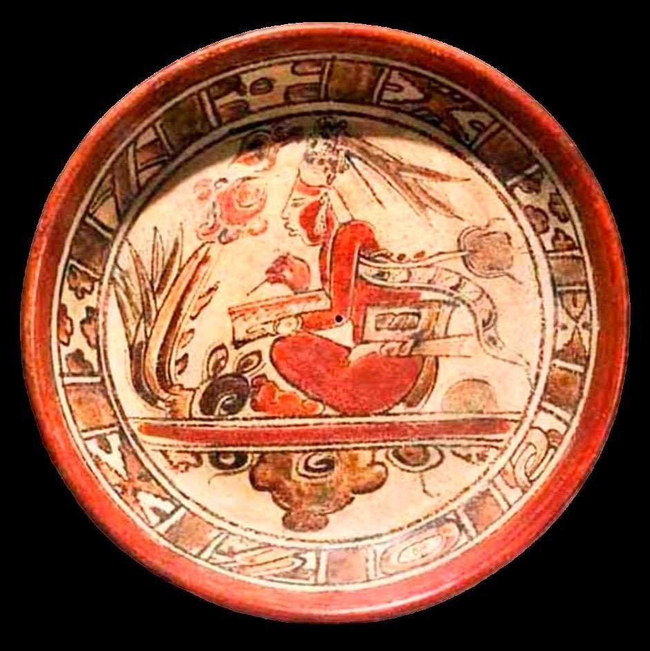 Plato maya policromado: un escriba sentado, vestido de rojo y con un tocado de plumas largas, escribe con el pincel en un códice abierto sobre una franja de agua; una banda celeste recorre el borde del plato