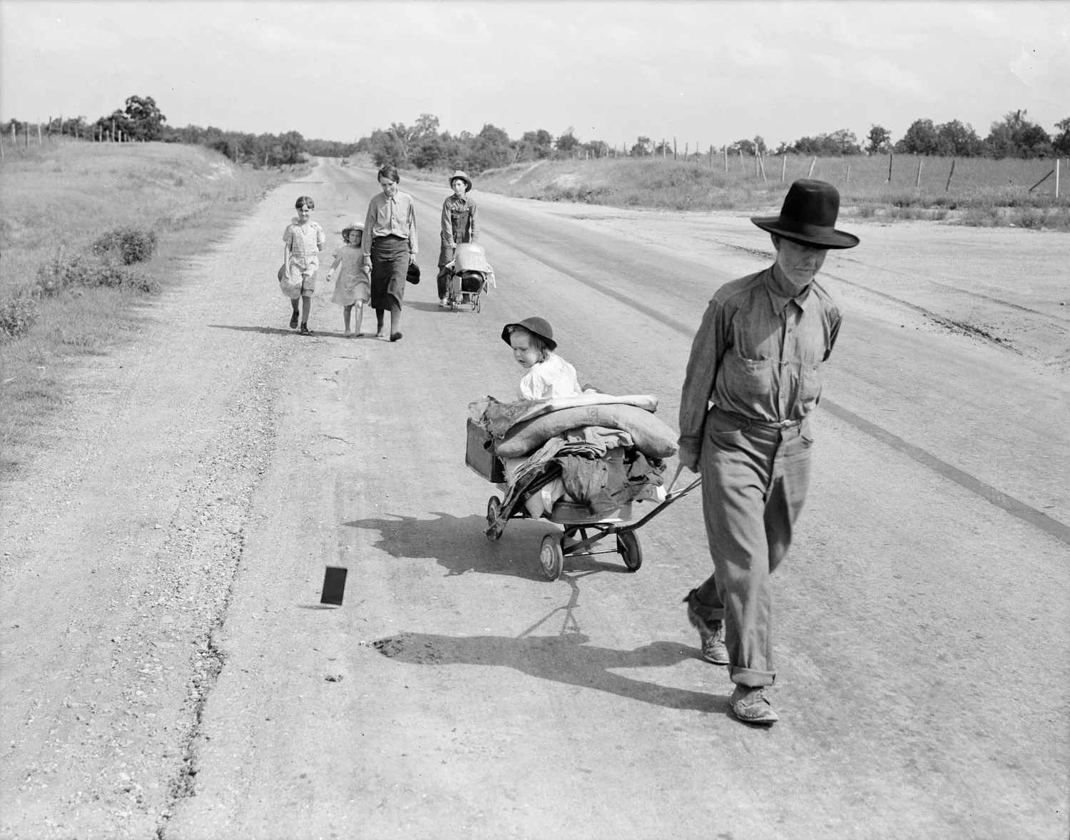 A mother and father walk along a highway with five children