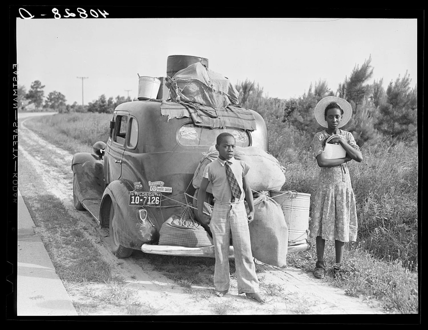Migrant workers gathered around a loaded car on a country road