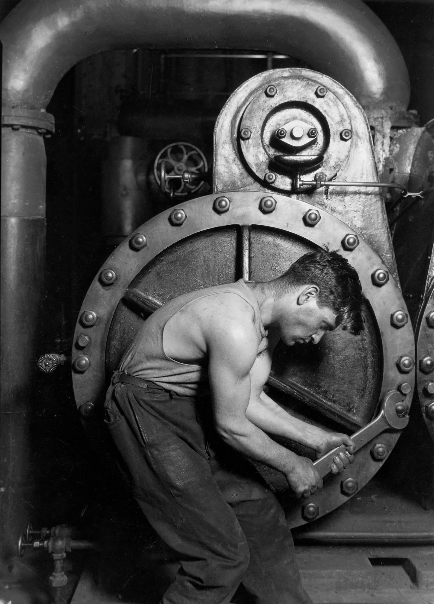 A mechanic tightens a bolt on a giant steam pump