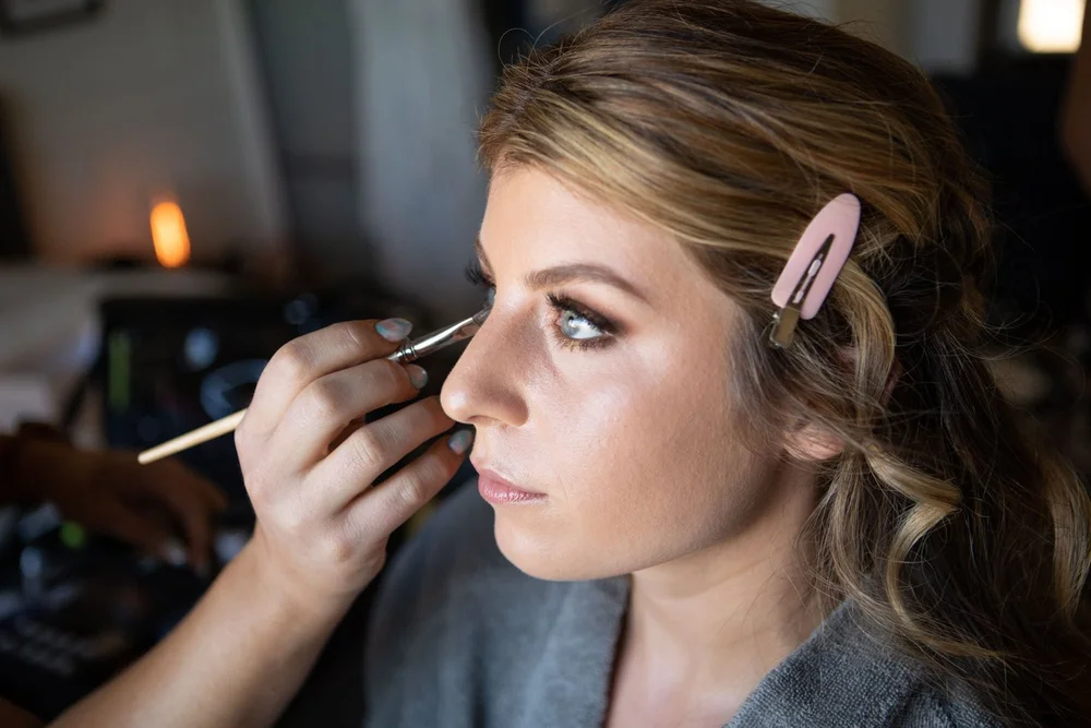 Bride having her makeup applied while getting ready for her desert wedding at Serenity Escape in Yucca Valley