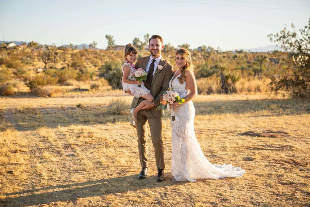 Wide landscape shot of bride and groom standing together in the desert with mountains in the distance at Serenity Escape in Yucca Valley