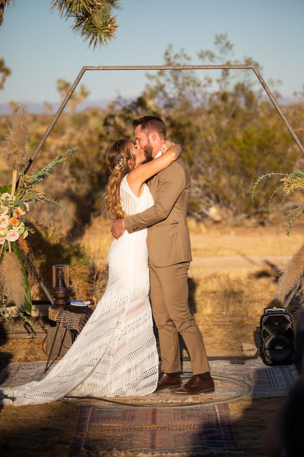 Bride and groom walking together through the wide open desert landscape at their Serenity Escape wedding in Yucca Valley