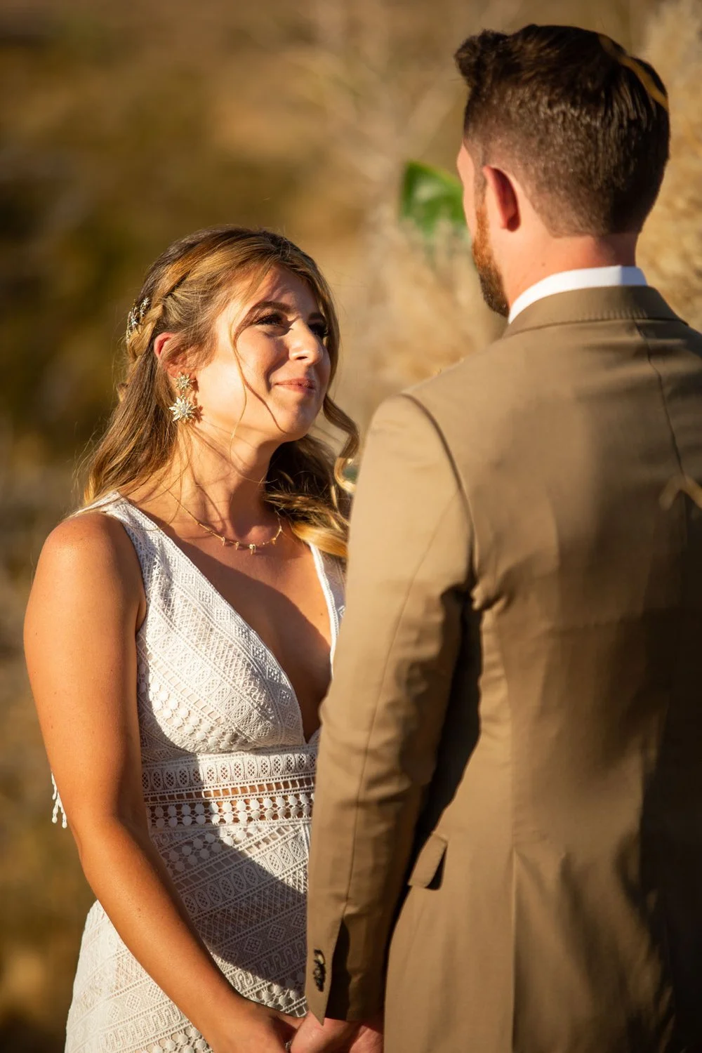 Bride and groom walking hand in hand on a wooden path surrounded by Joshua trees at golden hour at Serenity Escape in Yucca Valley