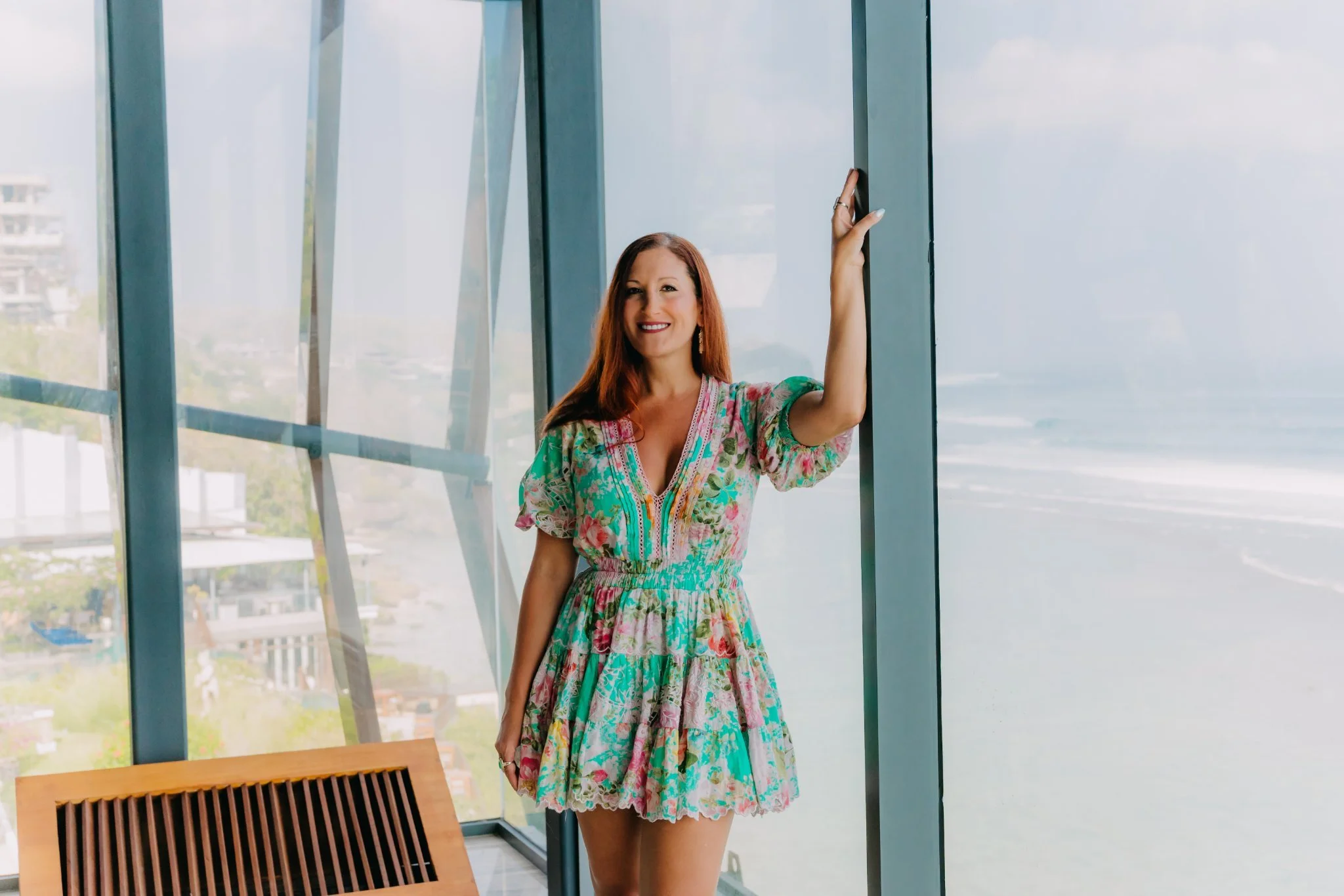 Laura standing in a glass room overlooking the Bali coastline
