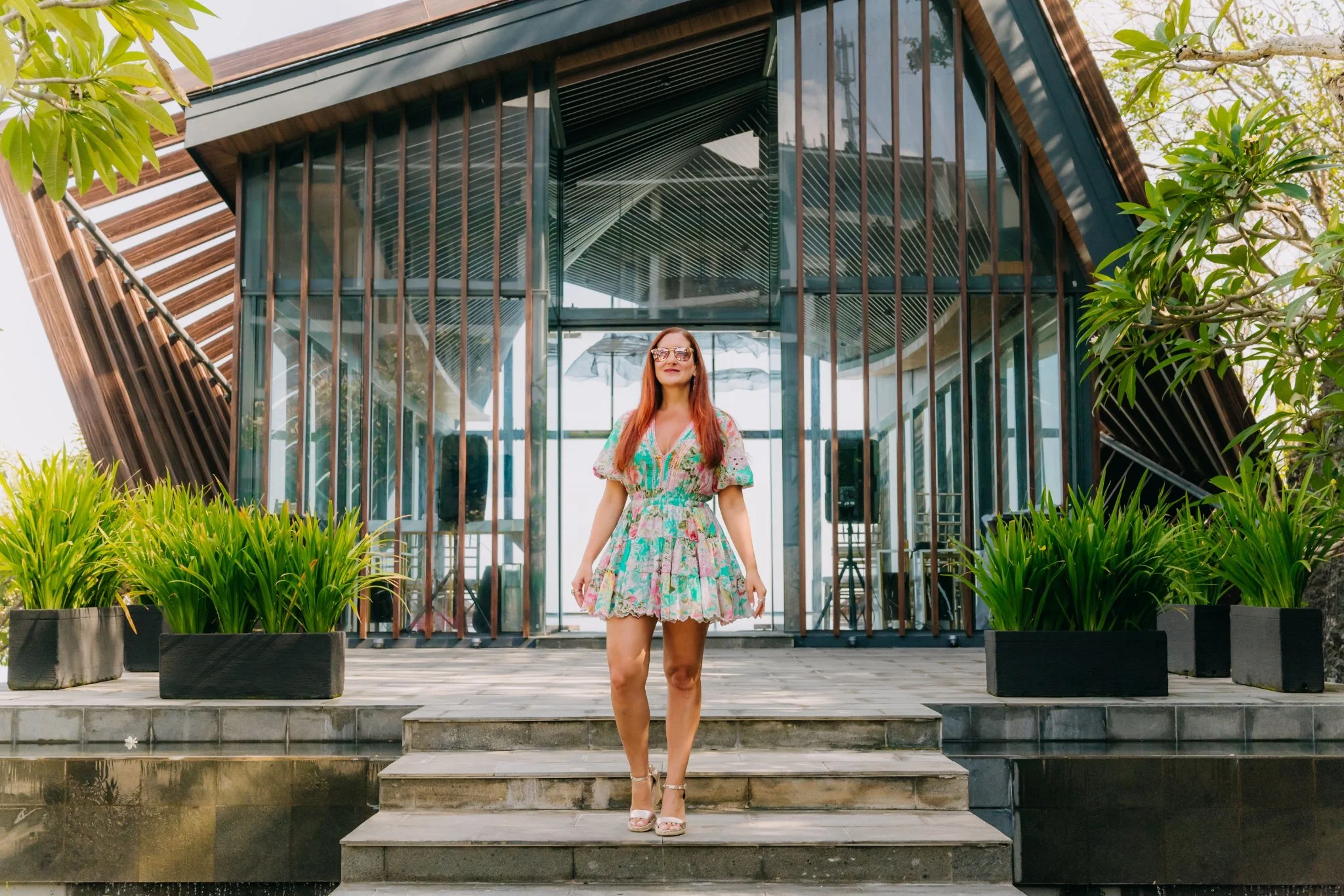 Laura standing on stone steps before a glass pavilion in Bali