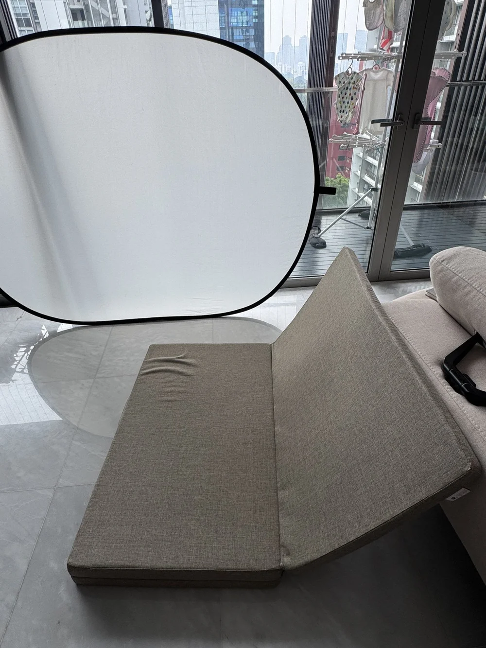 Large white reflector beside a sofa and balcony doors during a real home newborn photography session by Mamamiyo Photography in Singapore.
