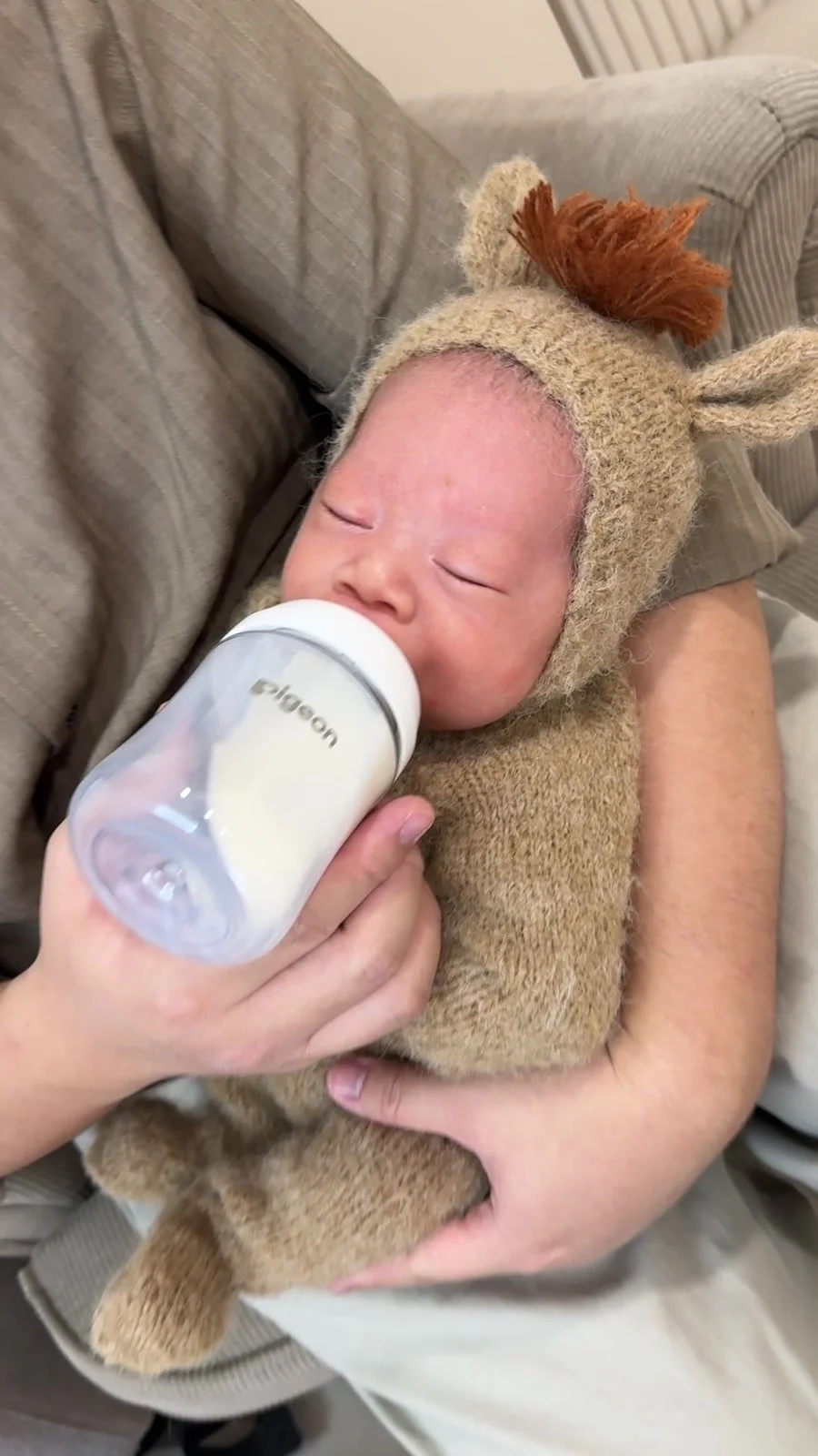 Newborn in a knitted animal outfit being bottle-fed during a break at a Mamamiyo home photoshoot in Singapore.