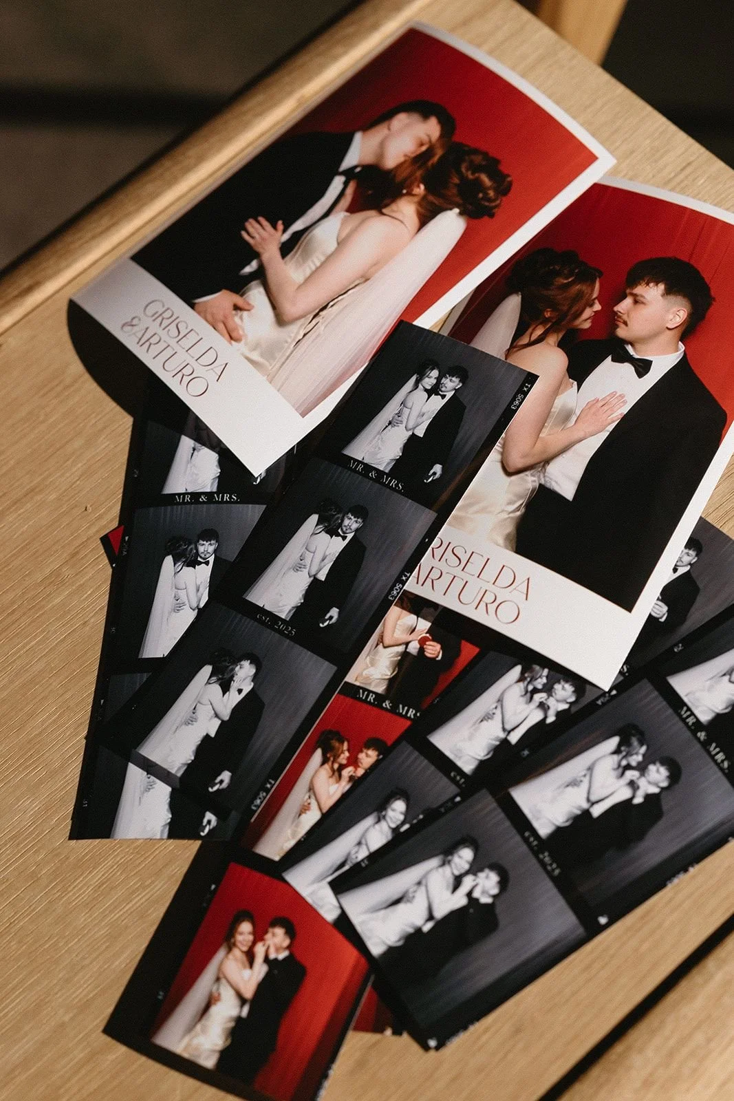 Stack of classic photo strips from a wedding photo booth set against red velvet curtains