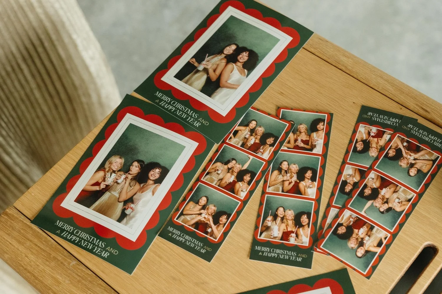 Holiday photo strips and Merry Christmas card prints fanned out on a wooden booth ledge