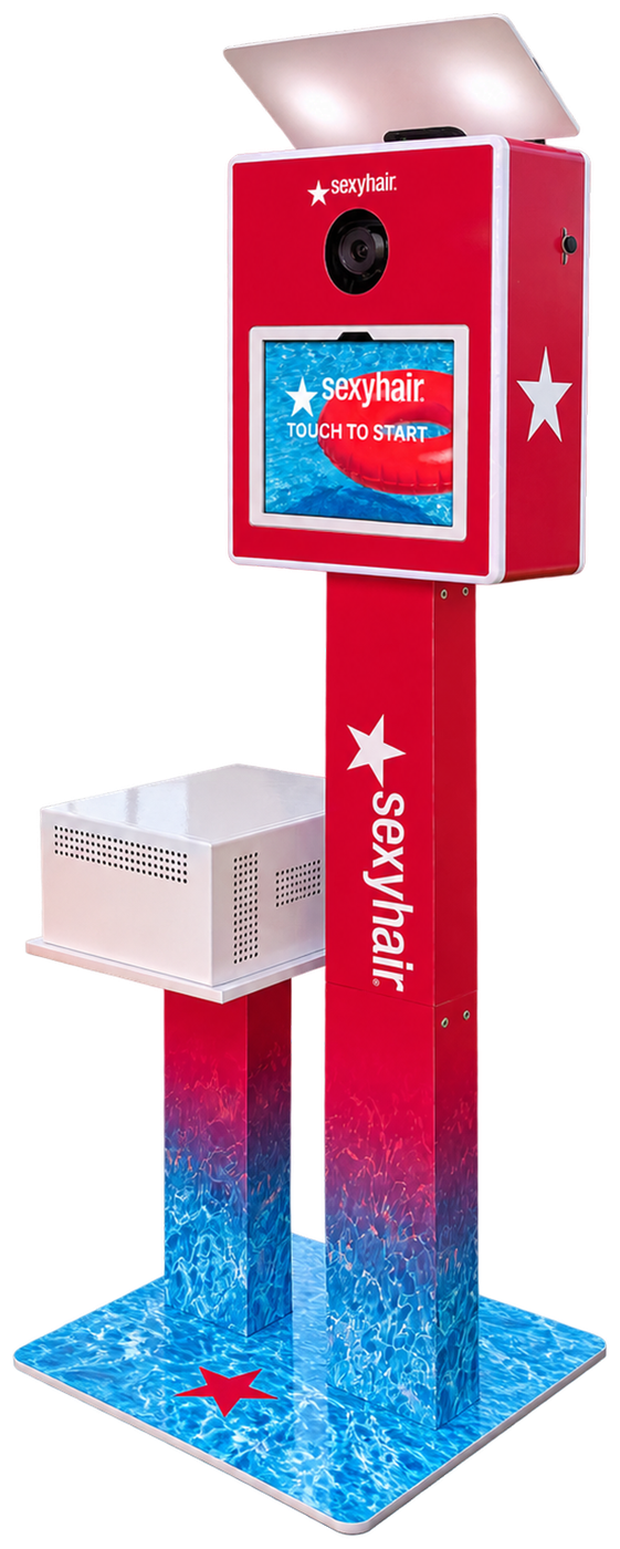 Front of the same open-air photo booth in a custom Sexy Hair wrap: red camera head, wordmark column fading into pool water