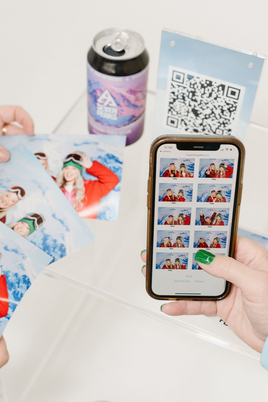 Guest scrolling a digital photo booth gallery on a phone next to a QR code sign