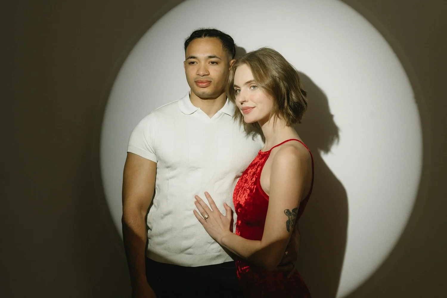 Couple posing for a glam photo booth portrait inside a circle of studio light