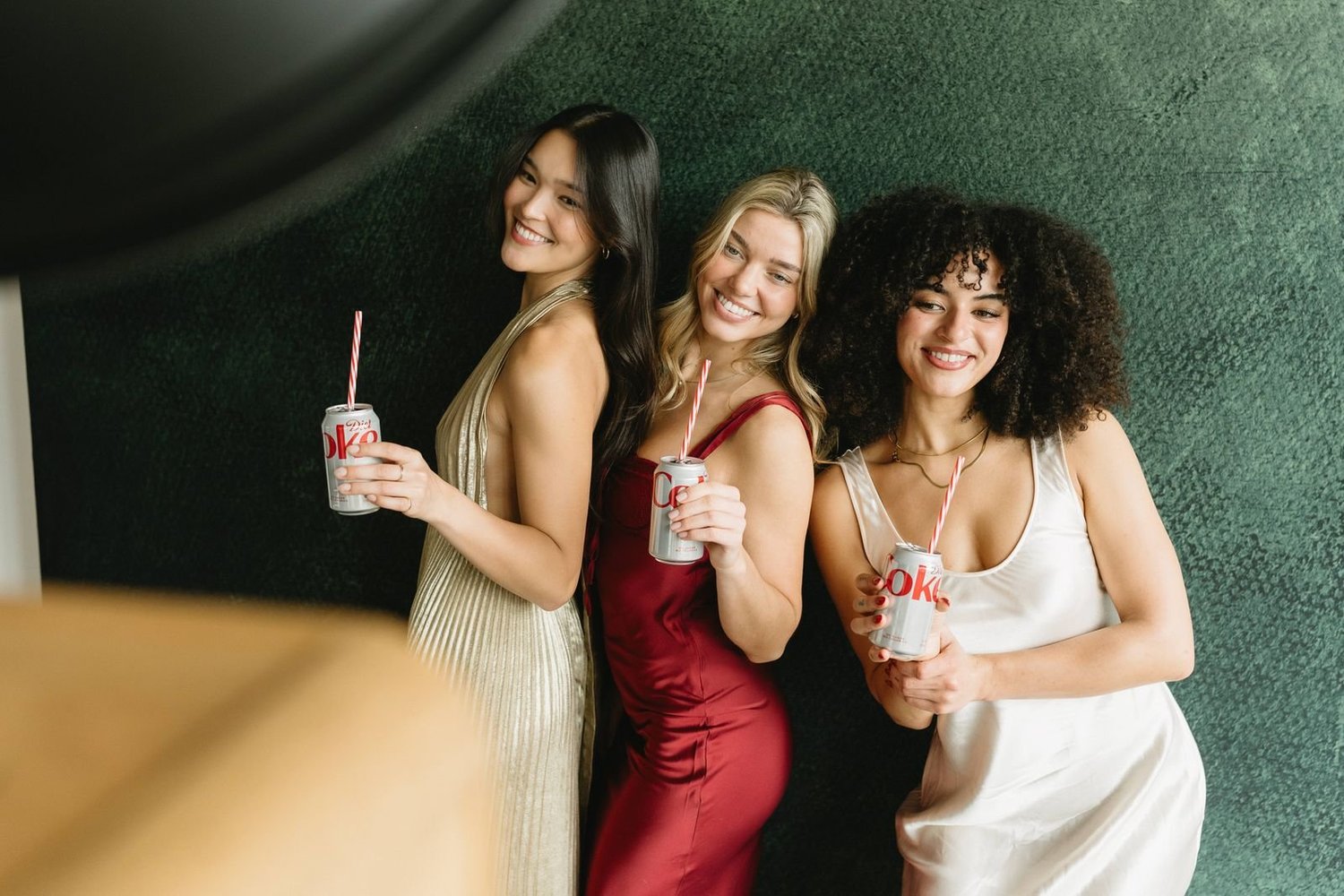Coworkers in holiday dresses posing at a photo booth with a deep green velvet backdrop