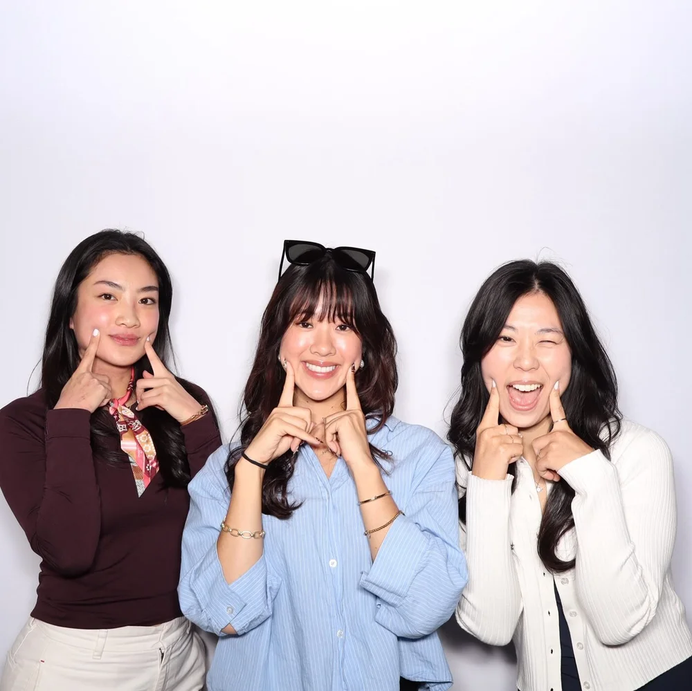 Three guests posing with finger frames in the open-air photo booth