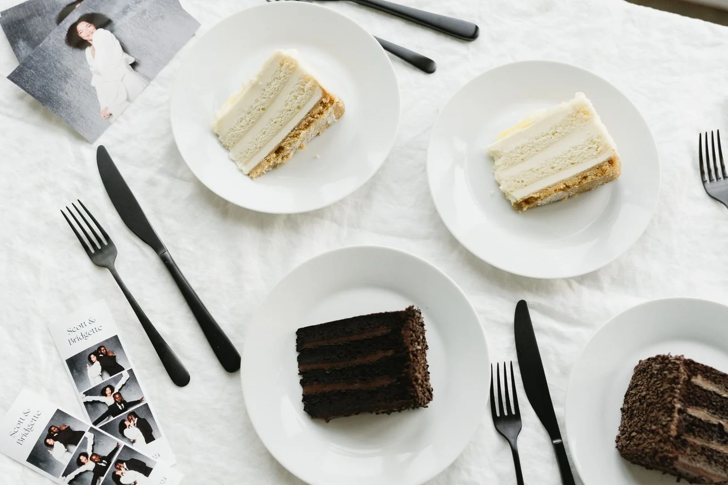 Slices of wedding cake beside black-and-white photo booth strips on the reception table