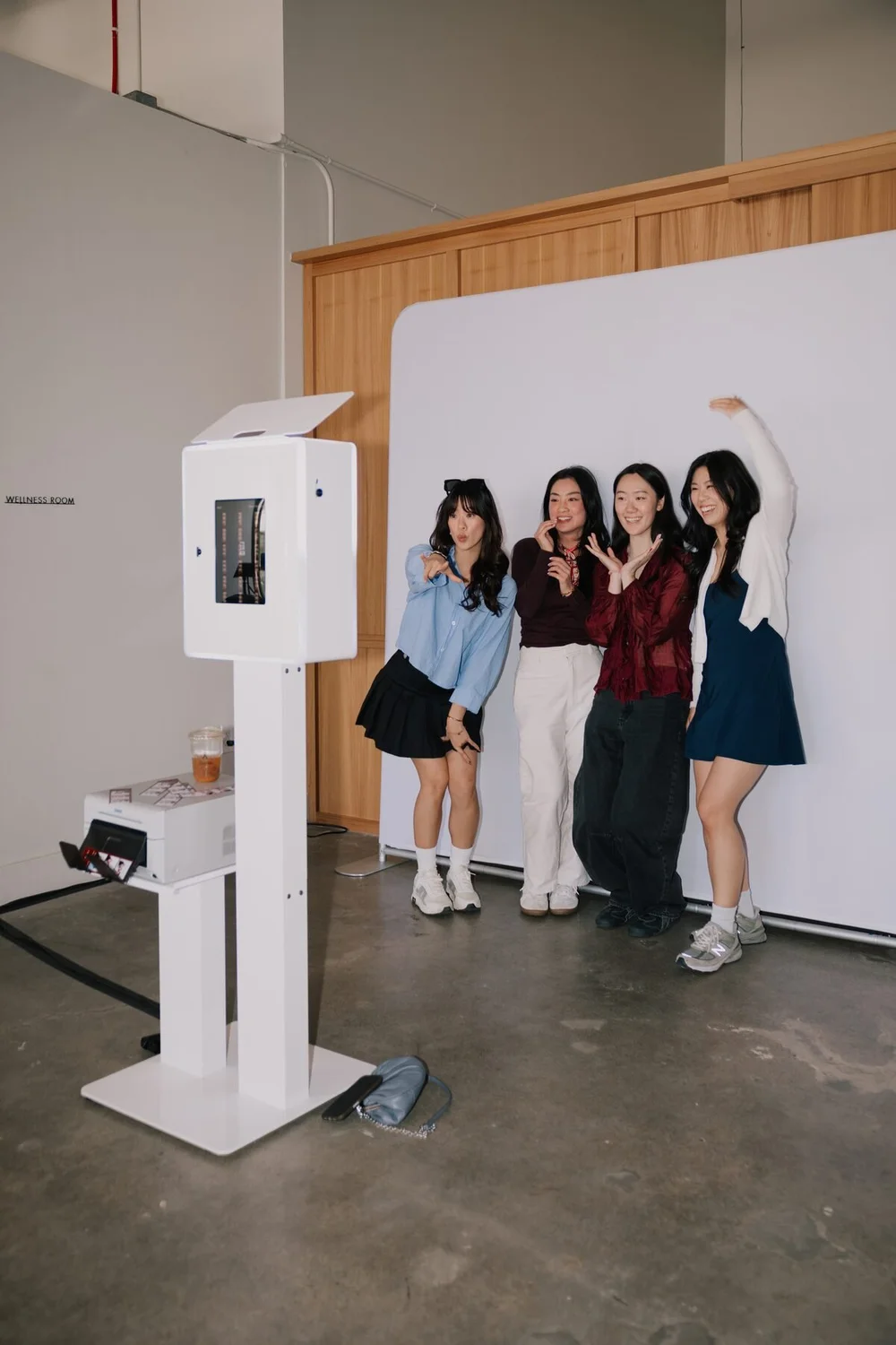 Four guests posing on the white backdrop beside the open-air photo booth at Ever Club