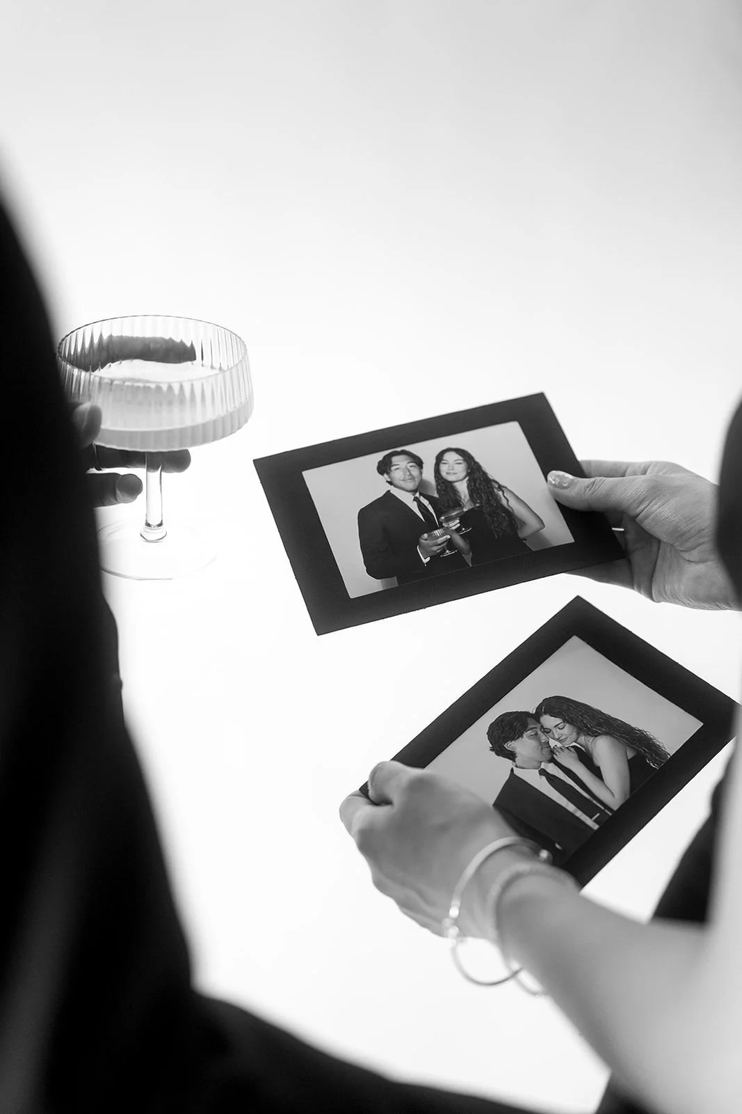Guests holding fresh black-and-white glam photo booth prints at a formal party