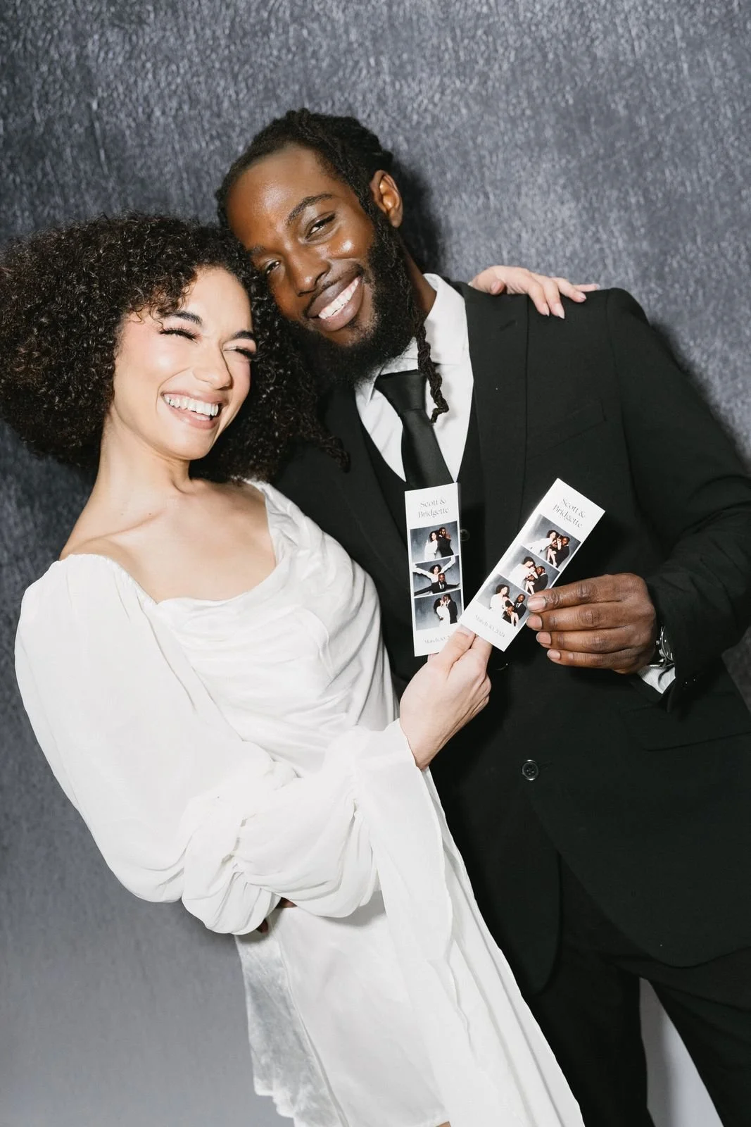 Newlyweds smiling over their photo strip at a wedding reception photo booth