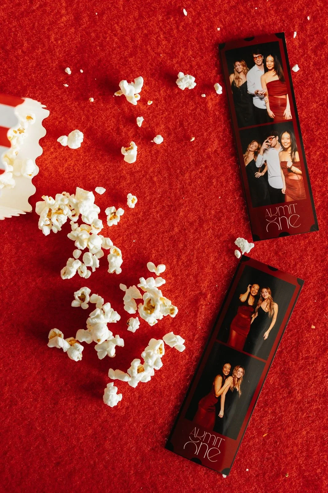 Retro photo strips and spilled popcorn on a red carpet at a movie-night party