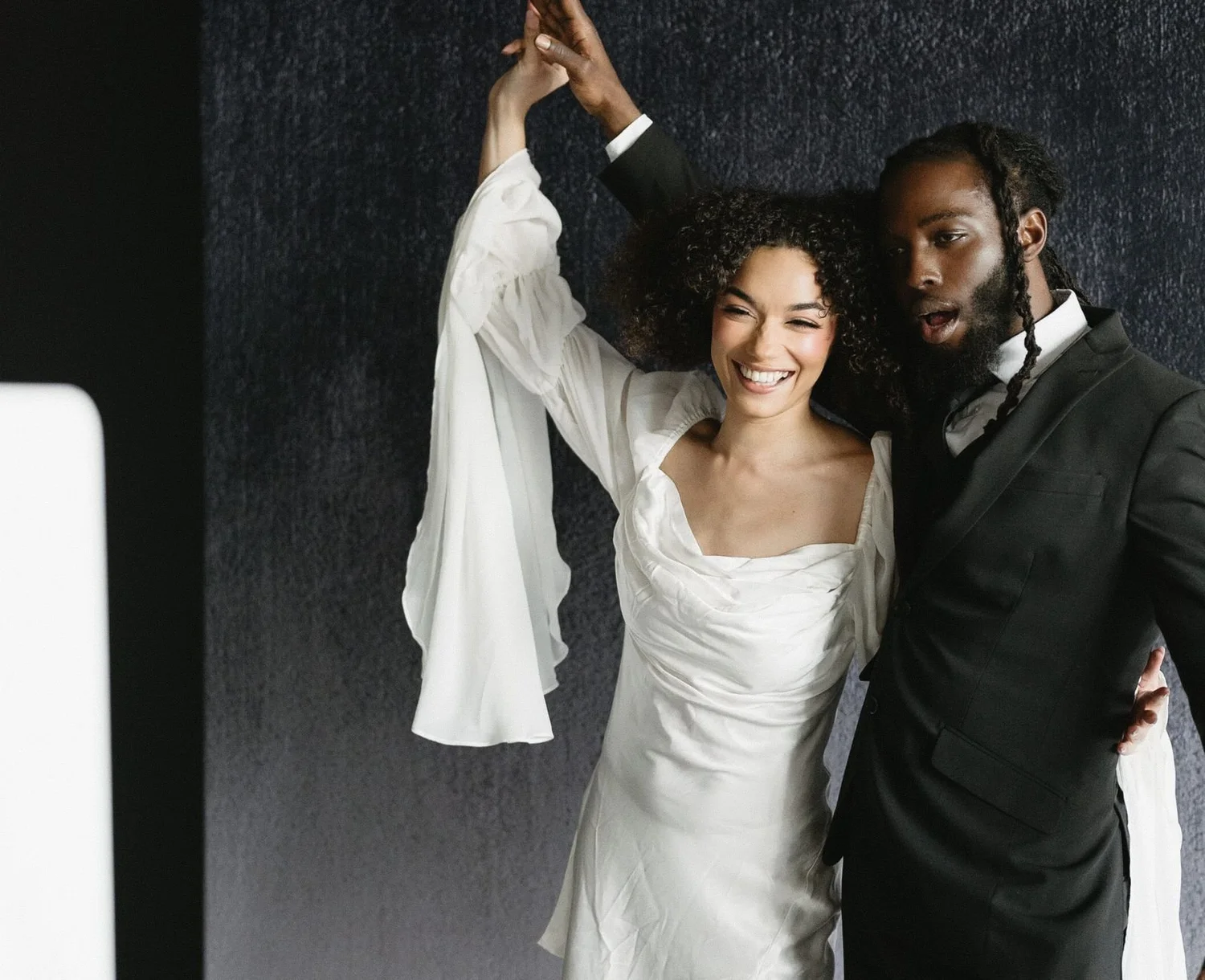 Bride in a flowing sleeved gown dancing with her groom at a wedding photo booth