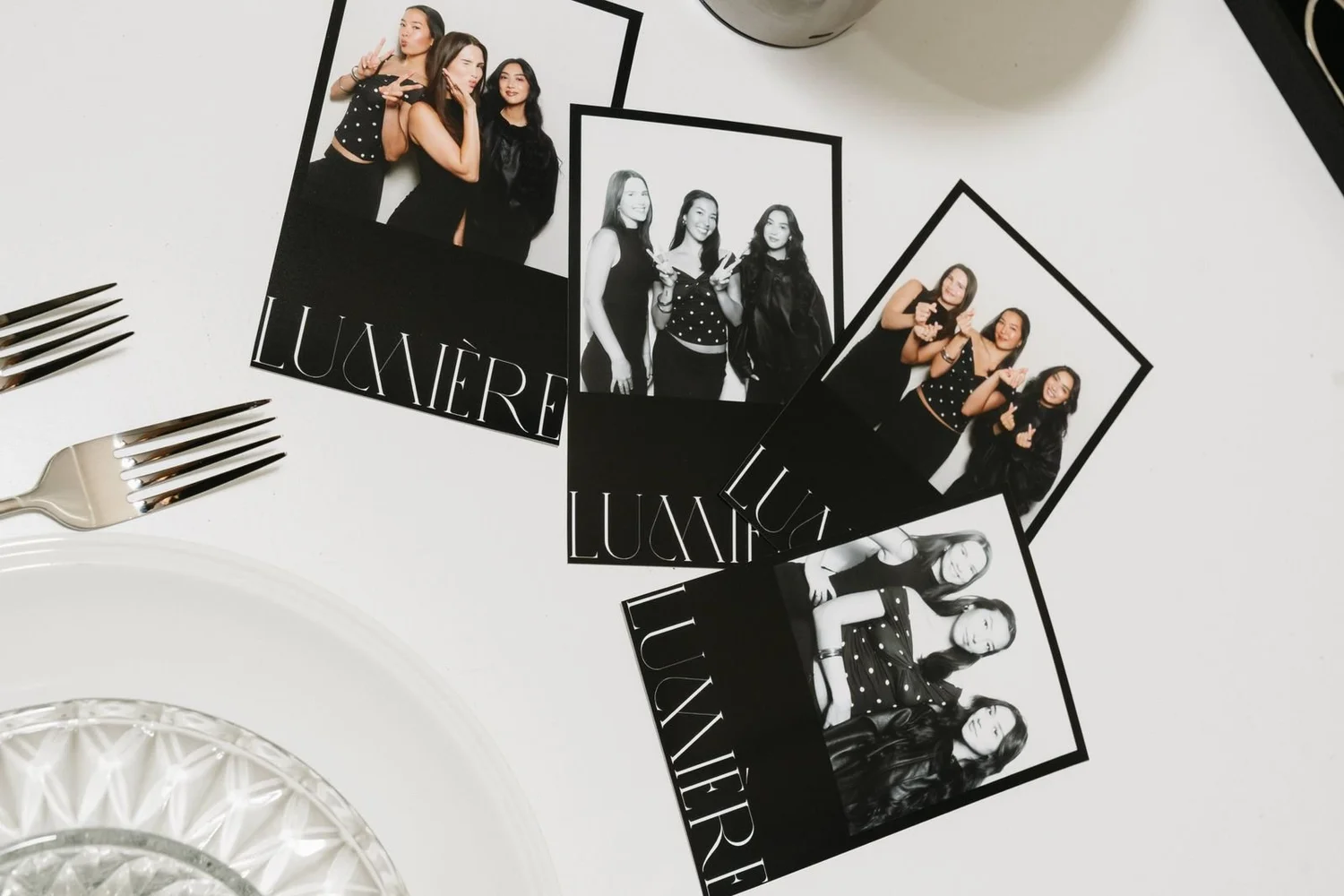 Black-and-white branded photo booth prints laid across a white dinner table beside silverware