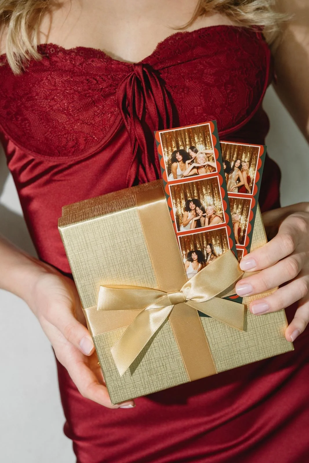 Guest holding a gold gift box topped with holiday photo booth strips