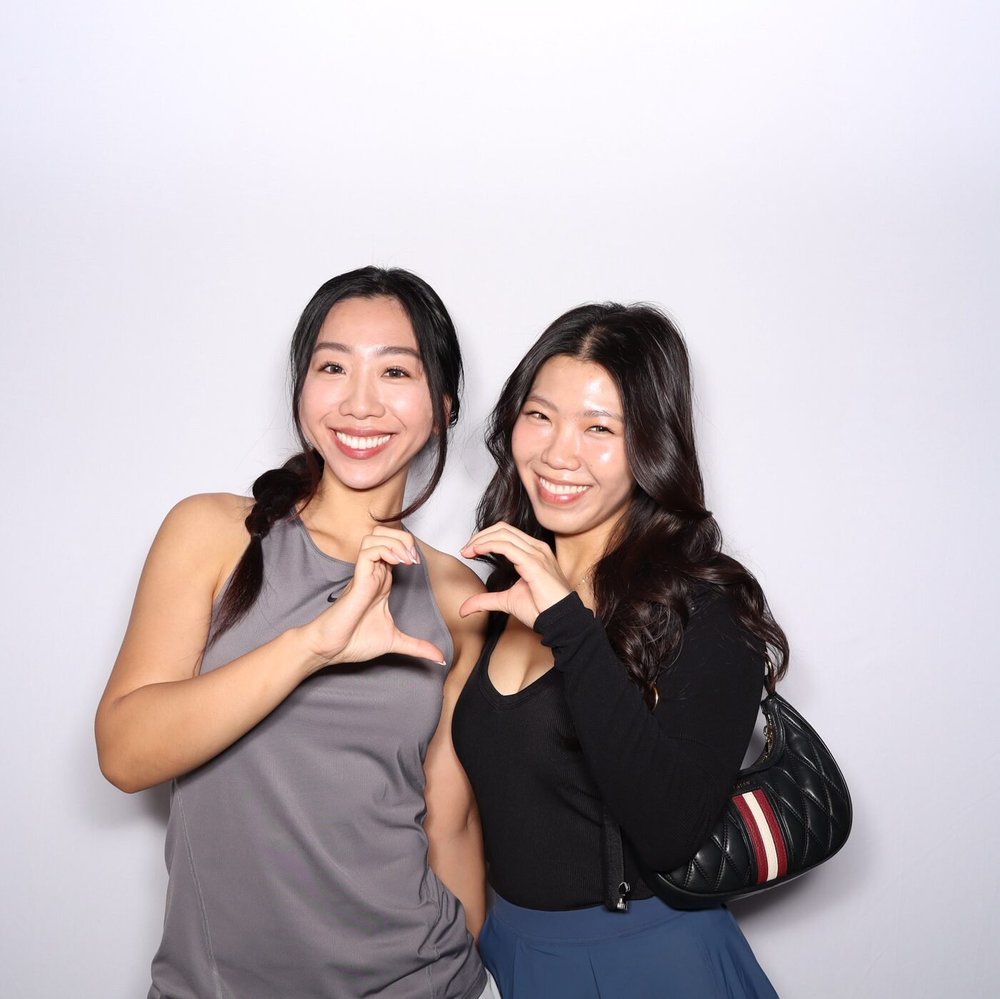 Two friends making hand hearts in the photo booth at Ever Club, Tustin