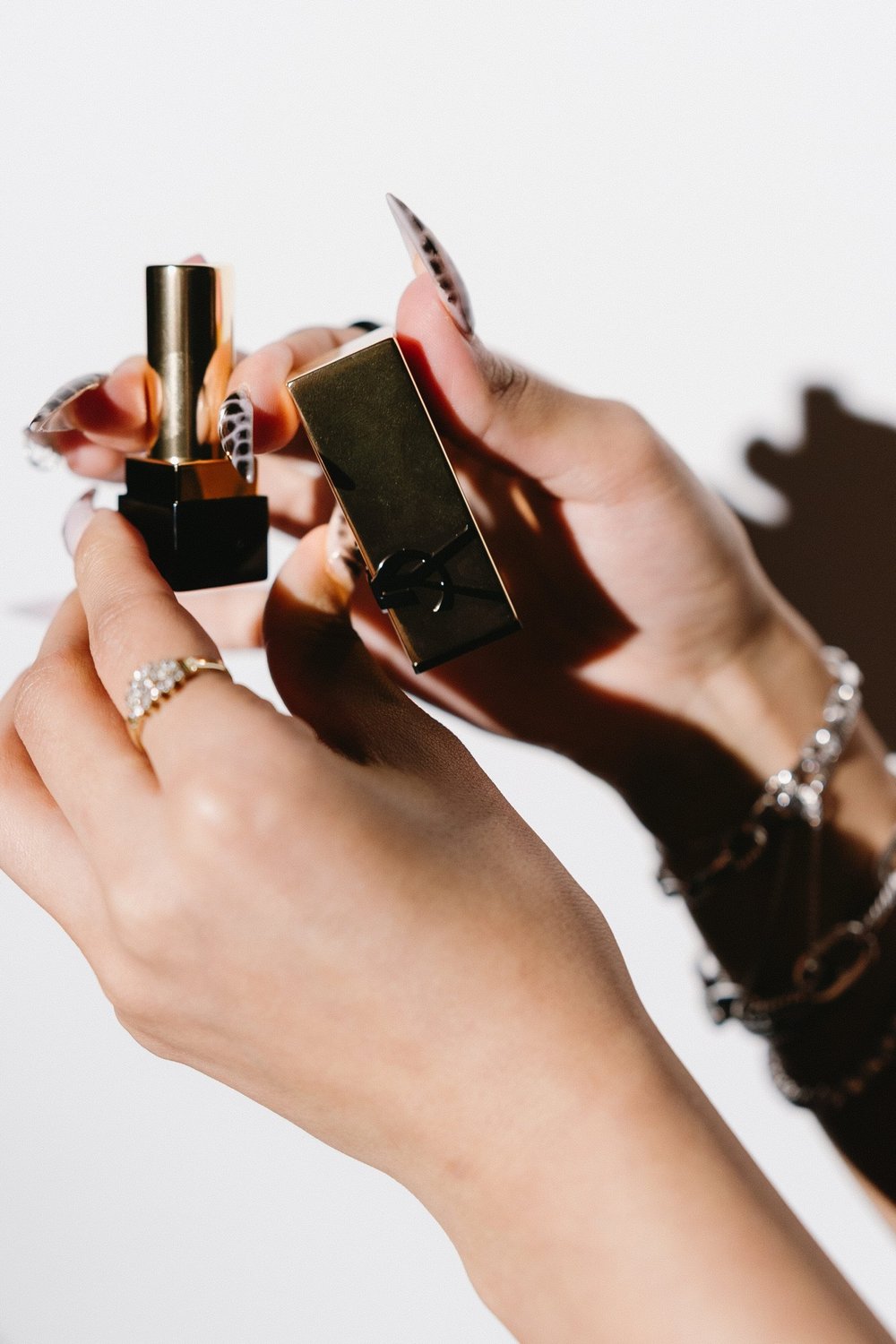 Close-up of hands holding a lipstick in hard studio light