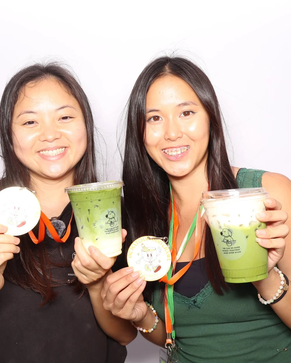 Two friends holding matcha and medals in the Ayer and Mind Over Miles photo booth