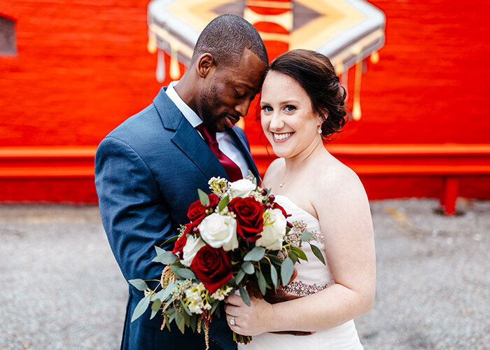 newlywed couple embraced with bouquet in front of mural wall tennessee wedding photographer