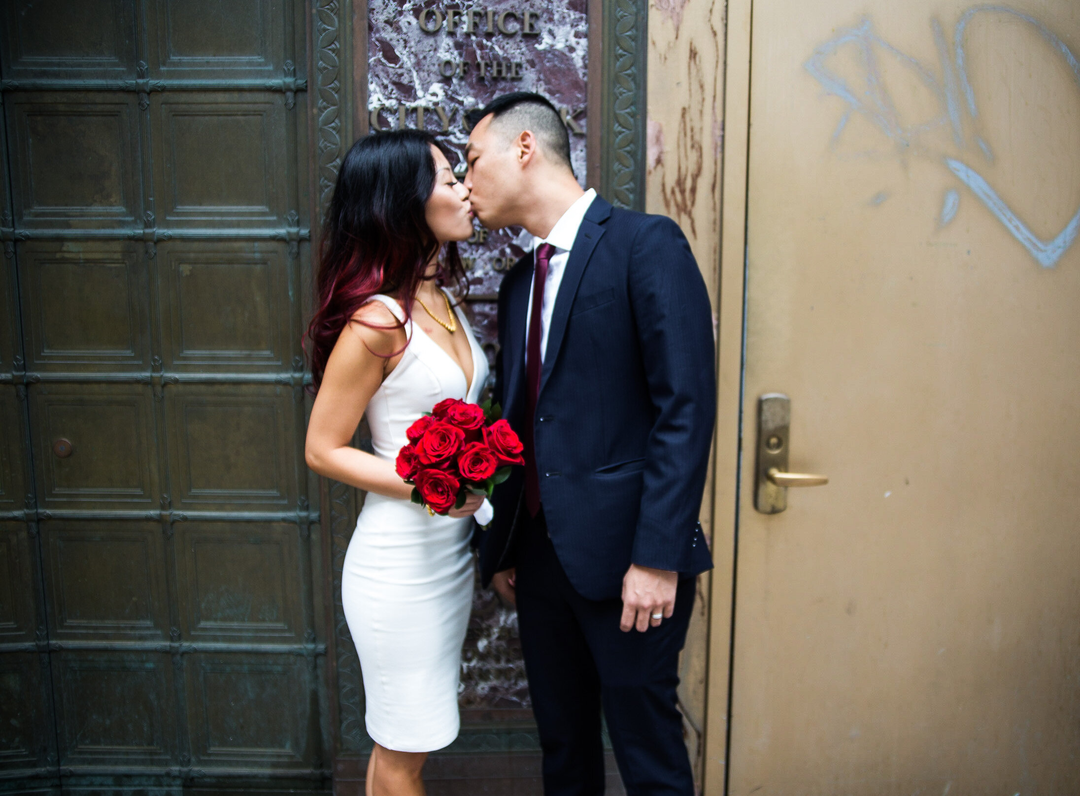 bride and groom kiss in front of new york city hall