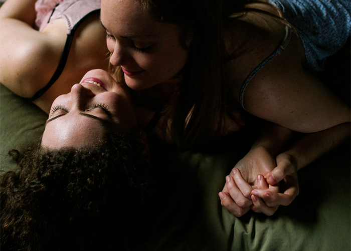 engaged couple lying on a bed and leaning to kiss portland oregon maddie maschger