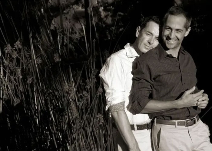 Two lovers in khakis and button ups embrace during engagement session holman photography